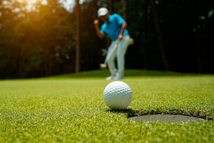 Golfer action to win after long putting golf ball in to the hole.