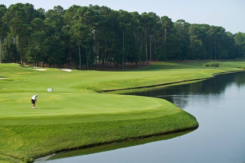 A man takes his final shot on a golf course.